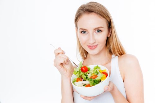 Pretty woman eating fresh salad isolated on a white background