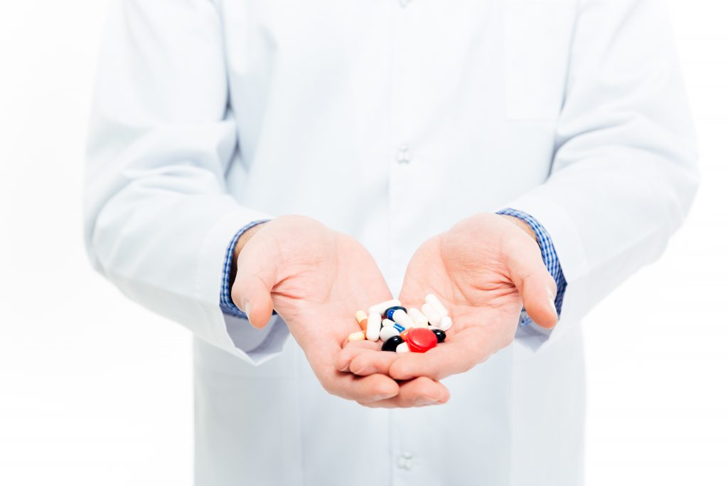 Male doctor holding pills isolated on a white background